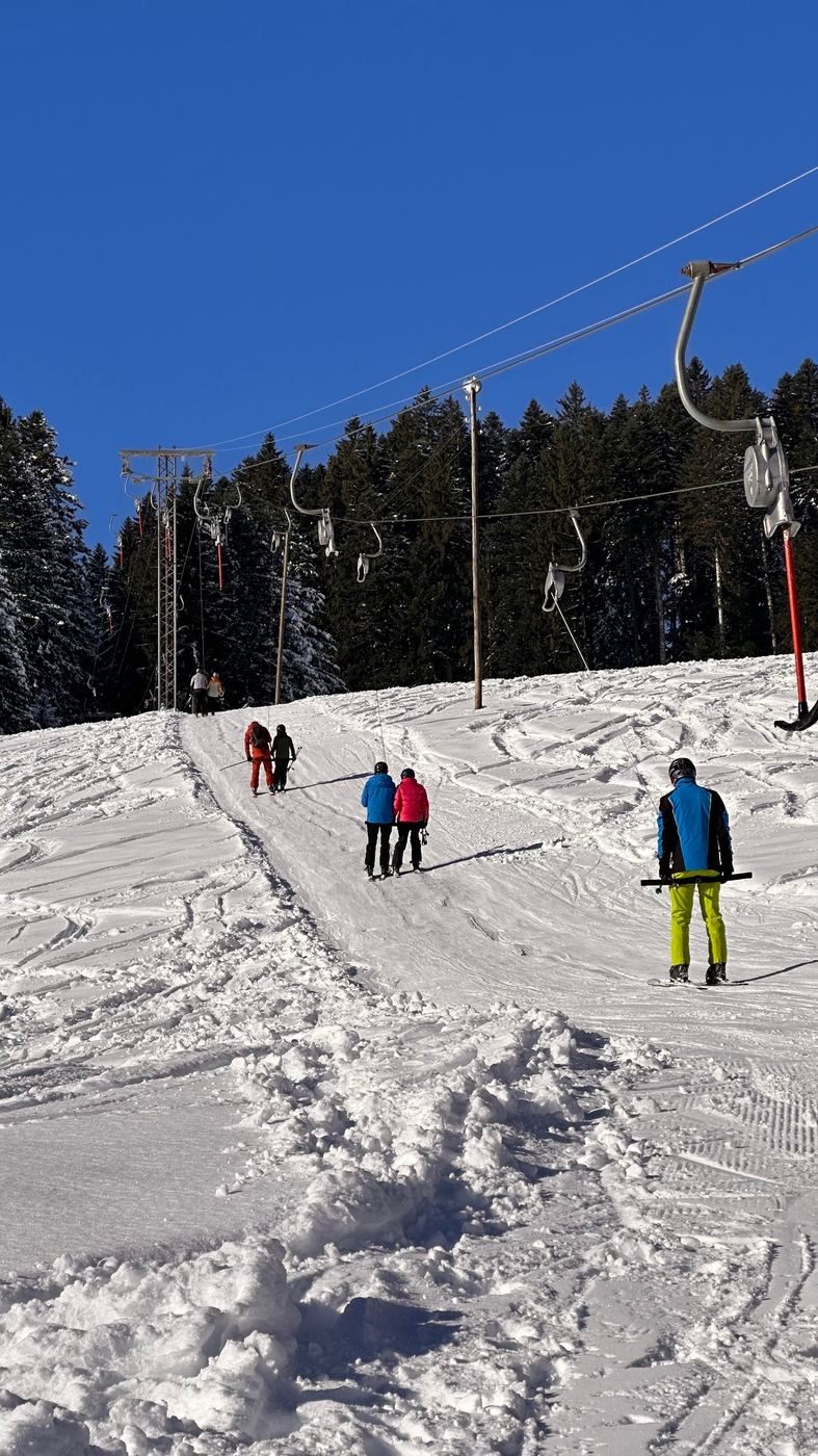 Mehrere Skifahrende am Bügellift unter blauem Himmel