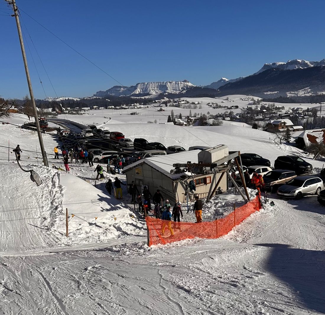Talstation mit Skilifthüttli und wartenden Kindern