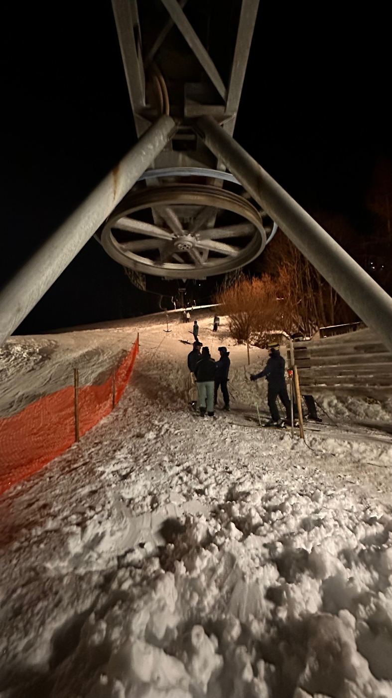 Skifahrende unter dem Umlenkrad in der Nacht