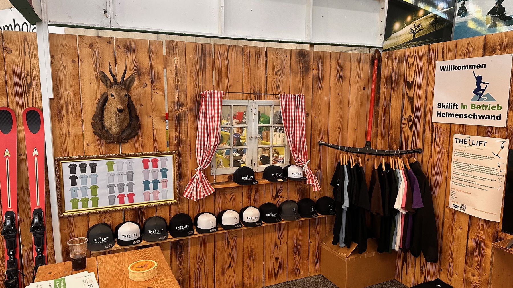 Der THE LIFT Stand mit Caps, T-Shirts und Hoodies an einer Holzwand